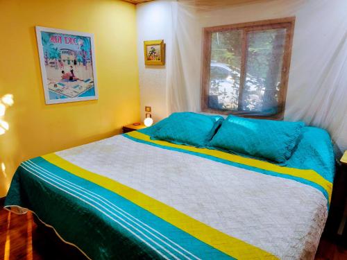 a bedroom with a bed with blue and yellow stripes at Excelsum Tayrona Garden Hotel in Calabazo