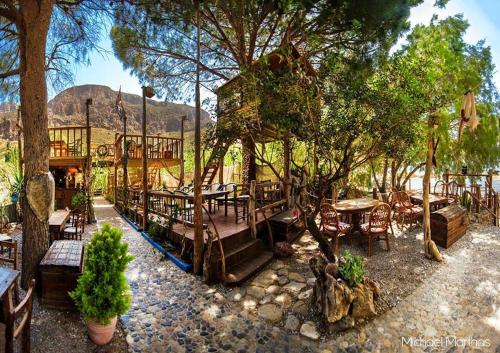 een terras met tafels en stoelen en een boom bij The Corsair Cottage in Kalymnos