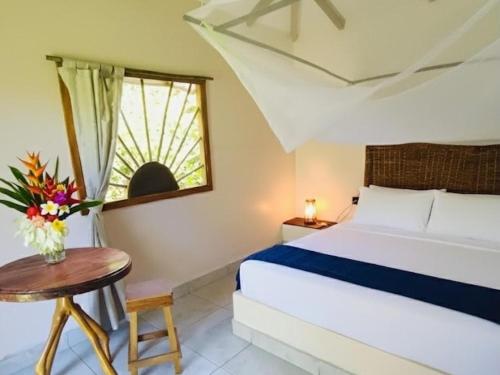 una camera da letto con un letto, un tavolo e una finestra di Pomelo Hostal a Dibulla