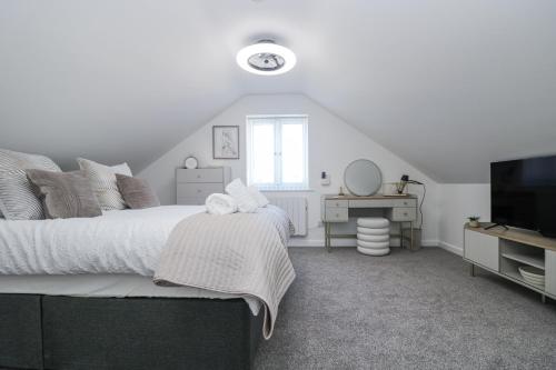 ein weißes Schlafzimmer mit einem Bett und einem Fernseher in der Unterkunft Cosy Retreat in Pool