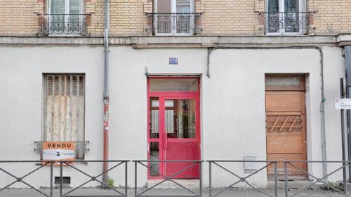 una porta rossa sul lato di un edificio bianco di Flower's Power a Vitry-sur-Seine