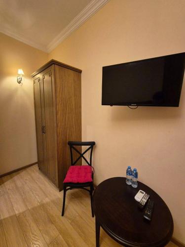 B&B rooms في تبليسي: غرفة بها طاولة وجهاز تلفزيون معلق على الحائط