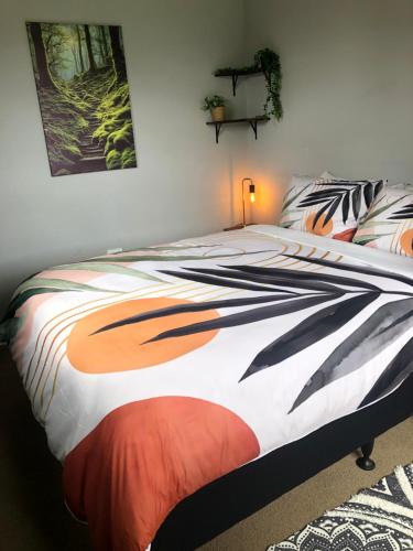 a bedroom with a bed with an orange and black comforter at Te Anau Holiday House in Te Anau