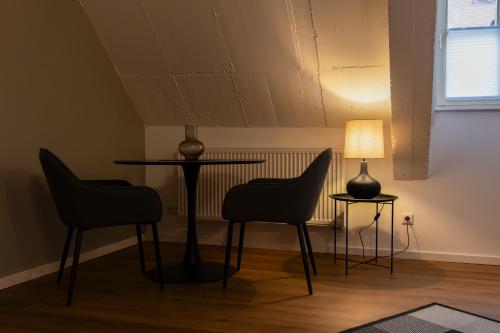 ein Zimmer mit zwei Stühlen und einem Tisch und einer Lampe in der Unterkunft BM Rooms Innenstadt - Große Moderne City Apartments mit eigenem Bad im Herzen der Stadt in Bamberg