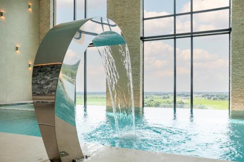 a fountain in a swimming pool with a window at Van der Valk Hotel Houten Utrecht in Houten