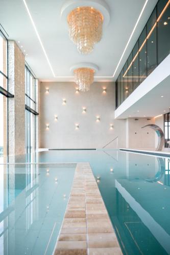a pool in a building with a chandelier at Van der Valk Hotel Houten Utrecht in Houten