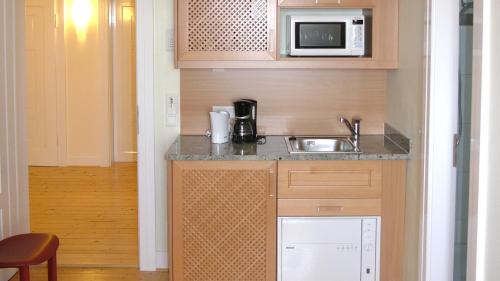 a small kitchen with a sink and a microwave at Villa Andante Apartmenthotel in Kassel