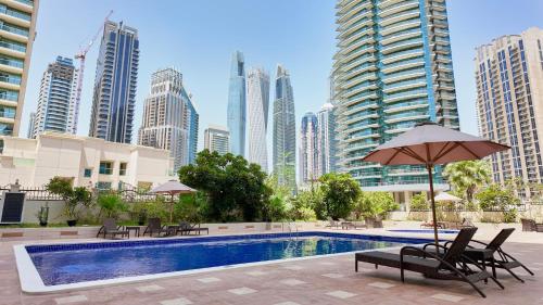 a pool with chairs and an umbrella in front of a city at Spacious Apartment Marina View in Dubai