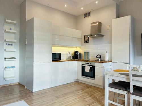 a kitchen with white cabinets and a table at Apartamenty Roztocze in Zwierzyniec