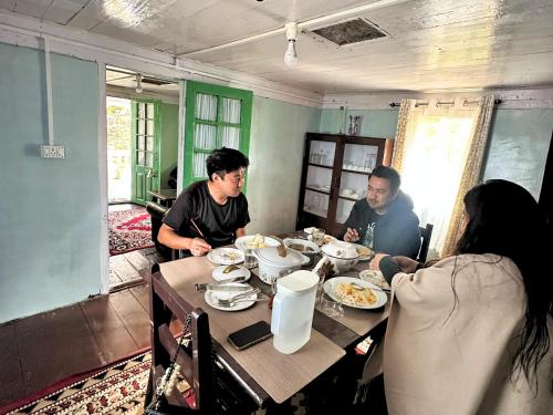 a group of people sitting around a table eating food at Mim Tea Estate Residency A 1920 Heritage Darjeeling Tea Garden Home in Sukhia Pokhari