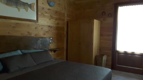 a bedroom with a bed with a wooden wall at Trout Lodge in Collagna