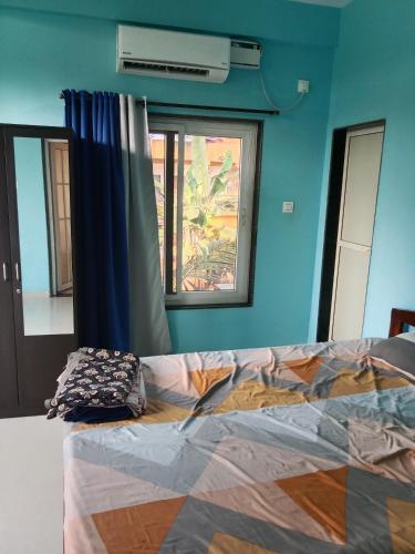 a bed in a room with a blue wall and a window at Casa De D'souza in Mandrem