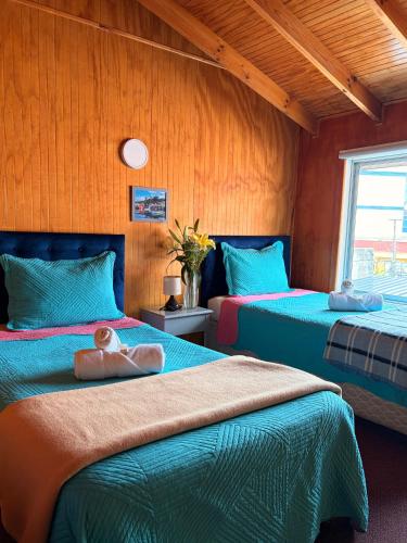 two beds in a room with blue and green at Hotel Gran Luna in Puerto Montt