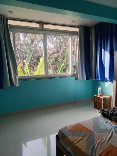 a bedroom with a window with blue walls and a bed at Casa De D'souza in Mandrem
