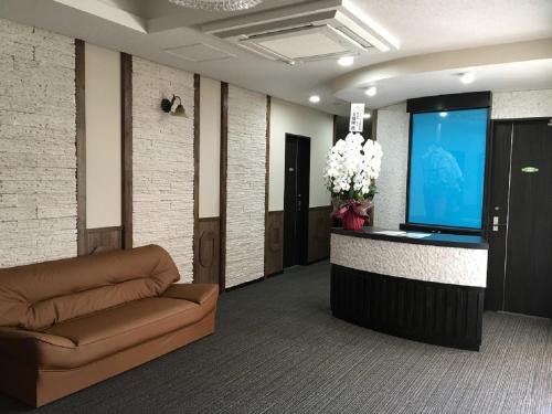 a lobby with a couch and a flat screen tv at Petit Hotel Blanc Fleur in Nakafurano