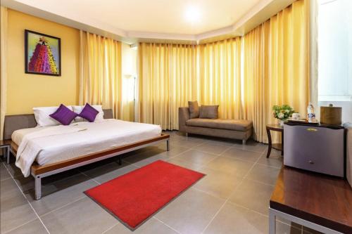a bedroom with a bed and a couch and a television at Maxlot Hotel in Accra