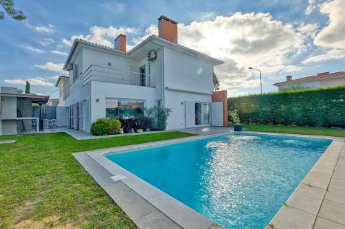 a house with a swimming pool in front of a house at Vita Portucale ! Aroeira 4 Bdr Pool & Golf Retreat in Aroeira