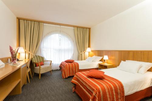 a hotel room with two beds and a desk at Hotel Jozef in Idrija