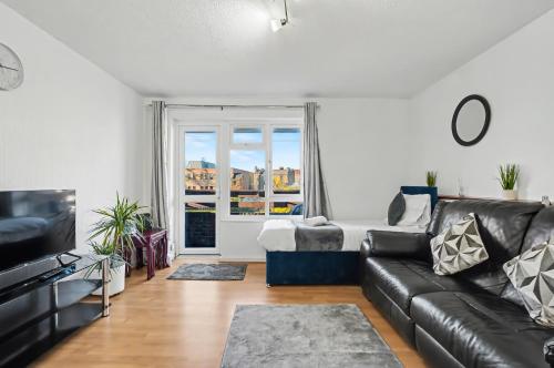 a living room with a black leather couch and a window at The Skyline Suite Tottenham in London