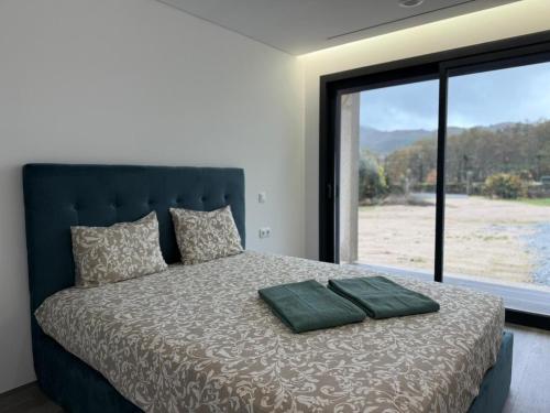 a bedroom with a large bed with a large window at Calcedonia House - Gerês in Terras de Bouro
