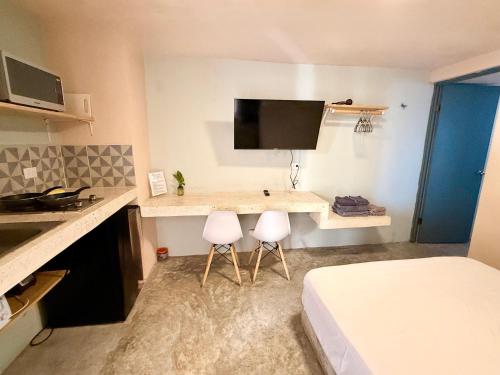Acogedor estudio con piscina في كانكون: غرفة نوم بسرير ومكتب مع كرسيين