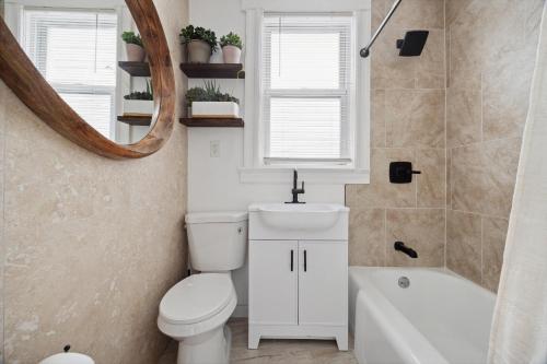 a bathroom with a toilet and a sink and a mirror at Spacious & Stylish 2BR Apartment Near Manhattan in Jersey City