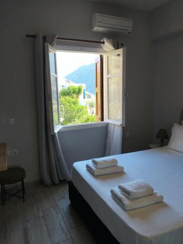 a bedroom with a large window with towels on a bed at Anasa house in Symi