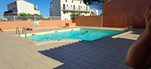 - une piscine avec 2 personnes dans l'eau dans l'établissement Maison dans résidence CopaCabana, à Saint Pierre La Mer
