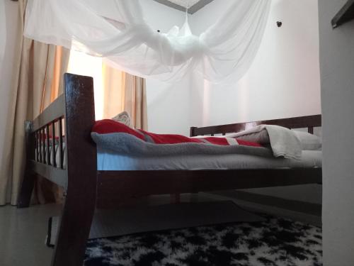a bedroom with a wooden bed with a curtain at TN apartments voism in Diani Beach