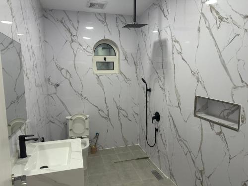 a bathroom with marble walls and a sink and a toilet at جناح عائلي غرفة وصول ذاتي in Al Hofuf