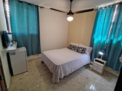 a small bedroom with a bed and blue curtains at Private and comfortable double room in Santo Domingo