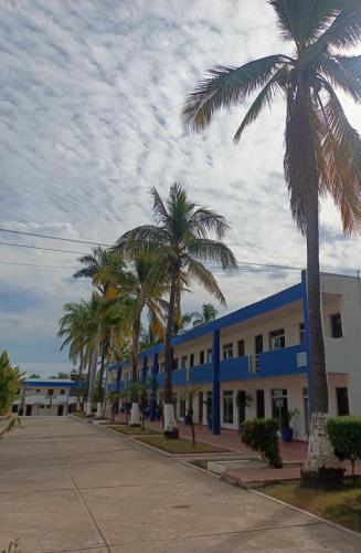 a blue building with palm trees in front of it at Hotel York in Guamúchil