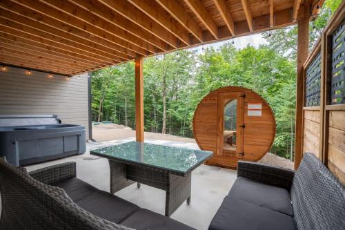 a patio with a table and chairs and a grill at Le Birdie spa et sauna in Saint-Faustin