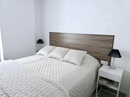 una camera da letto con un letto bianco con testiera in legno di Elegant Duplex Penthouse A116 a Las Lagunas Mijas