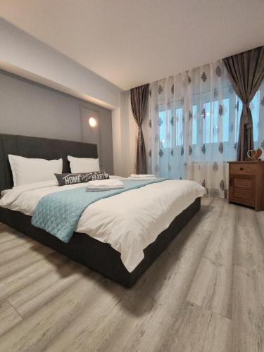 a bedroom with a large bed and wooden floors at Apartment Premium in Topliţa