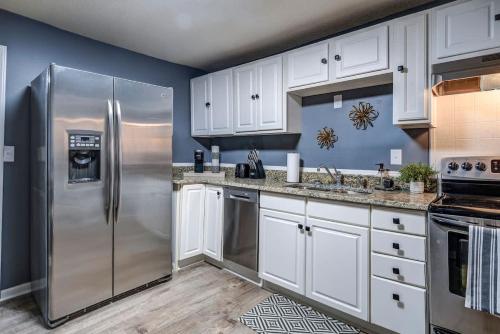 Charming 2 Bedroom Home by Founder's Park في جونسون سيتي: مطبخ بخزائن بيضاء وثلاجة من الفولاذ المقاوم للصدأ