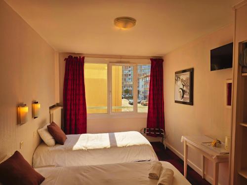 a hotel room with two beds and a window at Hôtel Alexandra Centre Ville in Boulogne-sur-Mer