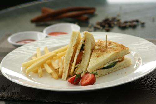 a white plate with a sandwich and french fries at Hotel Santika Bogor in Bogor