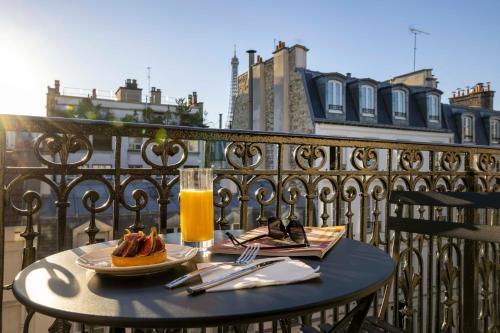 ein Tisch mit zwei Tellern Essen und einem Glas Orangensaft in der Unterkunft Grand Hôtel Lévêque in Paris