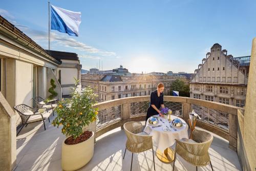 a woman standing at a table on a balcony with a view at Mandarin Oriental Savoy, Zurich in Zurich