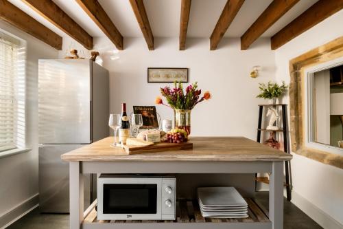 a kitchen island with a microwave and flowers on it at Magnolia Cottage-Exclusive Cotswold Package in Moreton in Marsh