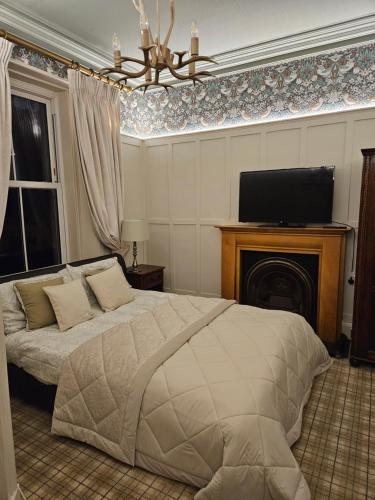 a bedroom with a bed with a television and a fireplace at Trinity Boutique B&B in Peterhead