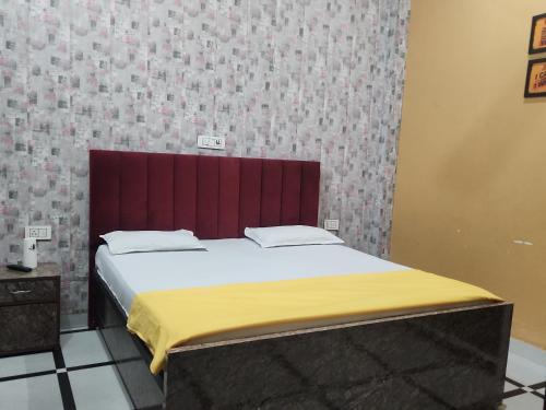 Bett mit rotem Kopfteil in einem Zimmer in der Unterkunft Panipat Town House - Top Rated Property of Panipat in Pānīpat