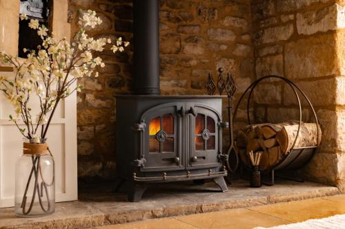 a wood stove in a room with a basket of wood at Magnolia Cottage-Exclusive Cotswold Package in Moreton in Marsh