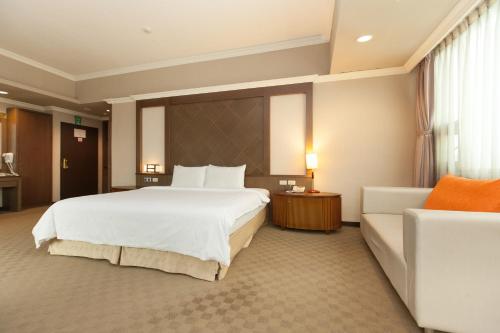 a hotel room with a large bed and a couch at F Hotel - Chiayi in Fanlu