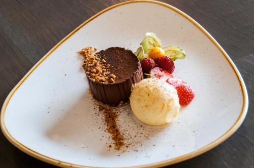 a white plate with a chocolate cupcake and strawberries at The Fleece Inn in Shireshead