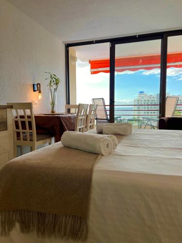 a bedroom with a large bed with chairs and a large window at Olimpia Sunset Studio in Costa de Adeje