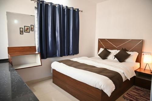 Schlafzimmer mit einem großen Bett und blauen Vorhängen in der Unterkunft Krishnayan Homestay in Ranchi