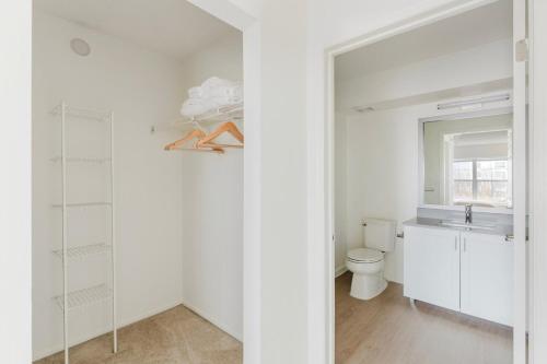 a white bathroom with a toilet and a sink at Blueground Hudson Exchange pool nr Liberty Park NYC-2174 in Hoboken