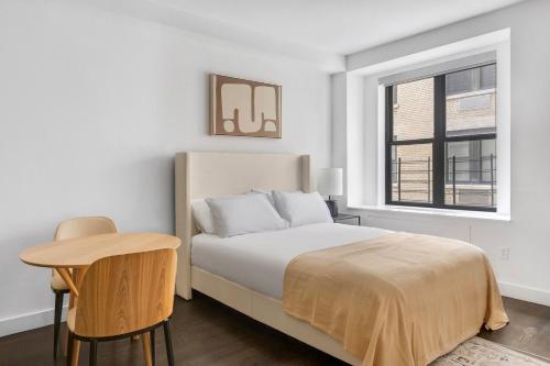 a bedroom with a bed and a table and a window at Blueground Upper West Side pool nr Central Park NYC-1960 in New York